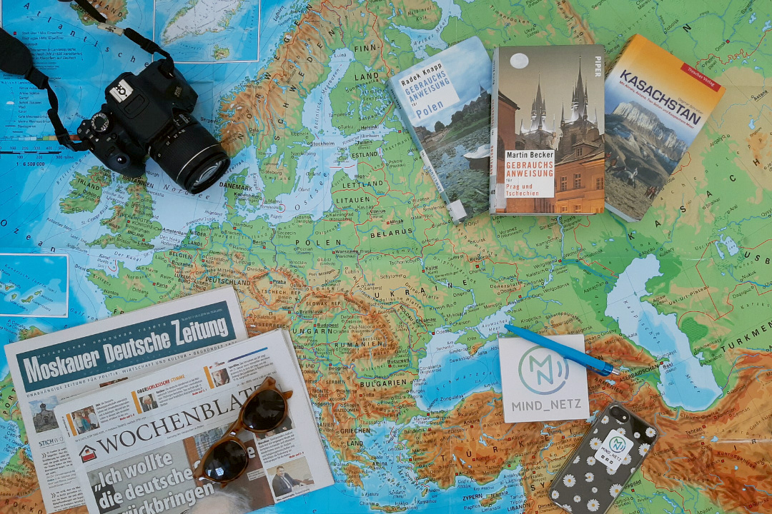Fotoapparat, Zeitungen und Reiseführer liegen auf Weltkarte