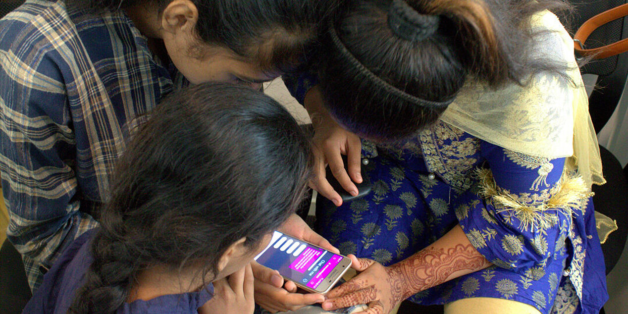 Drei pakistanische Mädchen nutzen die Plattform Aurat Raaj, die über die Gesundheit von Frauen informiert.