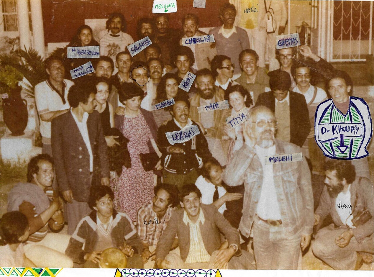 You can see a group photo. The people in the picture are laughing and appear cheerful. The photo is already yellowed and there are also small handwritten names on the picture.