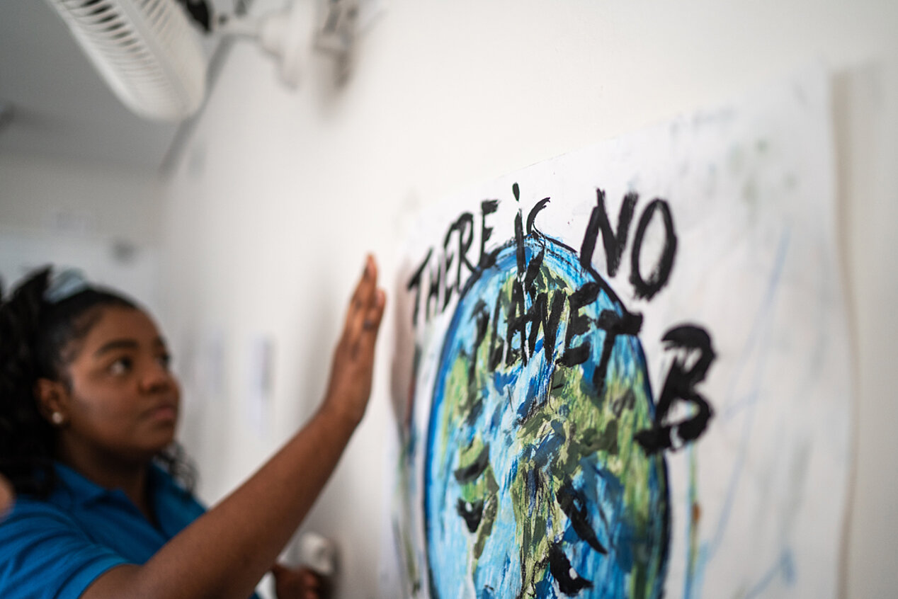 Woman standing in front of a poster with a globe and the words 'There is no planet B'.