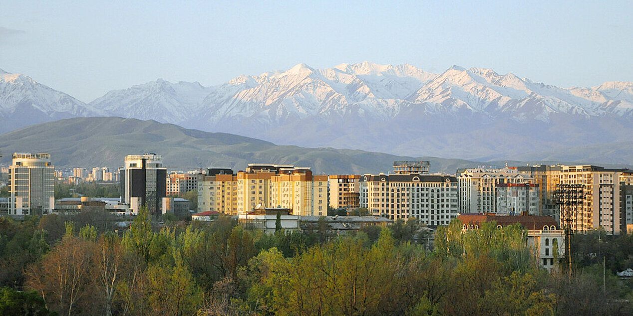 Im Vordergrund die Stadt Bishkek, Kirgistan, im Hintergrund schneebedeckte Berge.