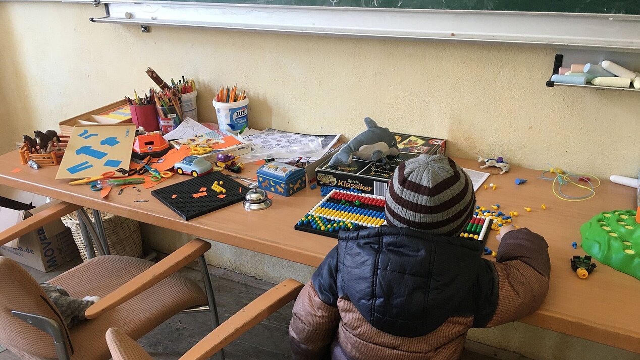 Junge sitzt am Schreibtisch bei Kinderbetreuung