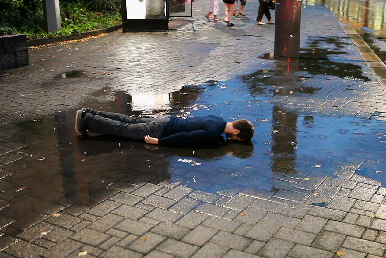 Ein Mann liegt mit dem Gesicht nach unten in einer Pfütze auf der Straße