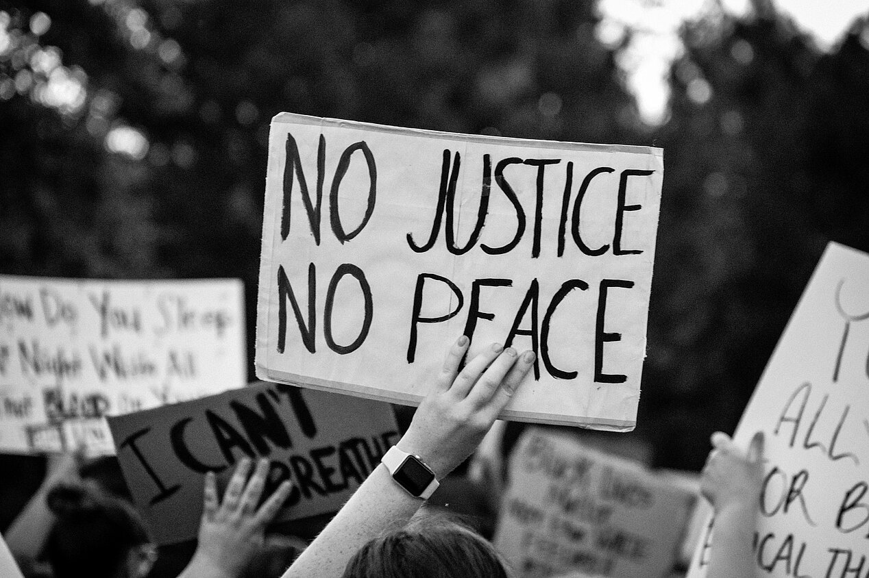 Demonstrant:innen bei einer Black Lives Matter Demonstration, 2020 in Nebraska. Auf dem Schild steht "Keine Gerechtigkeit, kein Frieden".